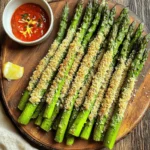 To make Air Fryer Parmesan Crusted Asparagus Fries, you need a few simple items. Gather these ingredients for a tasty snack or side dish: - 1 pound fresh asparagus, trimmed - 1/2 cup grated Parmesan cheese - 1/2 cup breadcrumbs (panko for extra crunch) - 1 teaspoon garlic powder - 1/2 teaspoon onion powder - 1/2 teaspoon paprika - Salt and pepper to taste - 1 large egg, beaten - Cooking spray Each ingredient plays a key role. The fresh asparagus gives a crisp base. The Parmesan cheese adds a salty, rich flavor. Panko breadcrumbs make the fries crunchy. The spices bring warmth and depth. The egg helps the coating stick. Cooking spray ensures everything crisps up nicely. Using quality ingredients is important. Fresh asparagus tastes best. Grated Parmesan should be fine, not the block. Panko adds that perfect crunch. You can tweak the spices based on your taste. Each element makes this dish special. Enjoy these fries hot for the best flavor! First, I preheat the air fryer to 400°F (200°C). This step takes about 5 minutes. Preheating helps the fries cook evenly. Next, I grab a shallow bowl. In it, I mix 1/2 cup of grated Parmesan cheese with 1/2 cup of breadcrumbs. I prefer panko for that extra crunch. I add 1 teaspoon of garlic powder, 1/2 teaspoon of onion powder, and 1/2 teaspoon of paprika. I season with salt and pepper to taste. I stir until everything is well mixed. Now, I take another bowl and beat 1 large egg until smooth. Each asparagus spear gets a dip in the egg. I make sure it’s coated well. Then, I roll the spear in the Parmesan mixture. I press gently to help it stick. I arrange the coated asparagus fries in a single layer in the air fryer basket. I spray them lightly with cooking spray. This step adds crispiness. I air fry them at 400°F (200°C) for 8 to 10 minutes. I shake the basket halfway through for even cooking. Once they are golden brown and crispy, I carefully take them out. I let them cool slightly before serving. To make your asparagus fries extra crispy, use panko breadcrumbs. They are lighter and crunchier than regular breadcrumbs. Another tip is to ensure the asparagus is dry. After washing, pat them with a towel. A light spray of cooking spray before cooking helps too. It gives the fries a nice golden look. Choose thin to medium-sized asparagus. They cook evenly and become tender quickly. If you pick thick spears, they may not crisp up well. Aim for spears around 1/4 inch thick. Trim the tough ends, about 1-2 inches, for the best bites. This way, they fry up just right. These fries shine when served hot. Pair them with marinara sauce or garlic aioli for dipping. A squeeze of fresh lemon juice adds a bright touch. You can also sprinkle chopped parsley or lemon zest on top for color. These extras make the dish even more appealing and tasty! {{image_2}} You can switch up the cheese to change the flavor. Try using Pecorino Romano for a saltier taste. If you want a creamier texture, use mozzarella. For a bold flavor, go for sharp cheddar. Each cheese will give your asparagus fries a unique twist. Experiment with what you like best. If you need a gluten-free option, use gluten-free breadcrumbs. You can also use crushed rice cereal or ground almonds. Both will add a nice crunch. This way, everyone can enjoy these tasty fries. Just make sure to check the labels for any hidden gluten. Add more flavor with extra spices. Try adding cayenne for heat or Italian seasoning for a herb blend. You can also toss in some lemon zest for a fresh taste. Mix and match to find your favorite combination. Each variation can keep your meals exciting and delicious. To keep your leftover asparagus fries fresh, place them in an airtight container. You can store them in the fridge for up to three days. Make sure they are completely cool before sealing the container. This helps prevent sogginess. You can also layer them with parchment paper to absorb any excess moisture. Reheating asparagus fries can be tricky. You want them crispy, not soggy. The best way is to use the air fryer again. Preheat your air fryer to 350°F (175°C). Place the fries in the basket for about 3-4 minutes. This method revives their crunchiness. You can also use a toaster oven. Set it to 350°F and heat for 5-6 minutes. If you want to save asparagus fries for later, freezing is a great option. First, cool the fries completely. Then, arrange them in a single layer on a baking sheet. Freeze them for about an hour. Once frozen, transfer them to a freezer bag. Remove as much air as possible before sealing. These fries can stay fresh in the freezer for up to three months. When ready to eat, cook them straight from the freezer in the air fryer, adding a couple of extra minutes to the cook time. I cook asparagus fries in the air fryer for 8 to 10 minutes. Set the fryer to 400°F (200°C). Check it halfway through and shake the basket. This helps them cook evenly. Look for a golden color and crisp texture. You can use frozen asparagus, but fresh is better. Frozen asparagus tends to be softer. If using frozen, thaw and dry it first. This helps the coating stick better. Adjust cooking time if needed. Parmesan crusted asparagus fries pair well with dips. Try marinara or garlic aioli for a tasty contrast. You can also serve them with a fresh salad or grilled chicken. They make a great side dish! You now have a quick and easy way to make tasty air fryer asparagus fries. We covered essential ingredients, like fresh asparagus and Parmesan cheese, alongside step-by-step instructions. I shared tips for extra crispiness and suggested fun variations. You can store any leftovers easily and reheat them for a delicious snack. Enjoy these flavorful fries with your choice of dips or as a tasty side. Make this dish a new favorite in your kitchen!