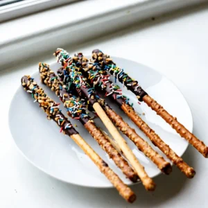 To make chocolate-covered pretzel rods, you will need a few simple items. Each ingredient adds flavor and fun to this treat. - 12 pretzel rods - 1 cup dark chocolate chips - 1 tablespoon coconut oil - 1/2 cup colorful sprinkles - 1/4 cup crushed nuts (such as peanuts or almonds) - Sea salt for sprinkling (optional) The pretzel rods provide a crunchy base. Dark chocolate chips bring rich sweetness. Coconut oil helps the chocolate melt smoothly. Colorful sprinkles and crushed nuts add a fun touch. A sprinkle of sea salt can enhance the flavor balance. Gather these ingredients before you start. It makes the process easy and fun! {{ingredient_image_1}} First, grab a baking sheet. Line it with parchment paper or a silicone mat. This makes it easy to lift the pretzel rods later. It also keeps them from sticking. Make sure you have enough space for all the rods. Next, get a microwave-safe bowl. Add 1 cup of dark chocolate chips and 1 tablespoon of coconut oil. The coconut oil helps the chocolate melt smoothly. Microwave the bowl in 30-second bursts. Stir after each burst until the chocolate is fully melted and shiny. Now, it&rsquo;s time to coat the pretzel rods. Dip each pretzel rod into the melted chocolate. Make sure to cover it well. Let the extra chocolate drip off. This step is key for a nice coating. While the chocolate is still wet, it&rsquo;s time to decorate. You can roll the rods in colorful sprinkles or crushed nuts. This makes them look fun and tasty. Make sure to coat them evenly for the best look. Once you finish coating all the pretzel rods, place them on the lined baking sheet. If you like, sprinkle a tiny bit of sea salt on top for a sweet and salty taste. Put the baking sheet in the fridge for about 30 minutes. This helps the chocolate set hard. When done, you can take them out and enjoy! To get a smooth chocolate coating, use coconut oil. Mix it with your chocolate chips. This helps the chocolate melt evenly. Heat your mixture in short bursts. Stir often to keep it silky. If the chocolate gets too thick, add a little more coconut oil. I love using dark chocolate chips for this recipe. They provide a rich taste. You can also use milk or white chocolate if you prefer. Just make sure it's good quality. Quality chocolate melts better and tastes great. Get creative with your toppings! Use colorful sprinkles for a fun look. Crushed nuts add a nice crunch. You can mix and match toppings for variety. Try adding a drizzle of melted chocolate on top too. It makes them look fancy. Serve these pretzel rods on a nice platter. They make great snacks for parties. You can also wrap them in clear bags for gifts. They are fun for kids&rsquo; parties or movie nights. Enjoy them fresh or store them for later! Pro Tips Use Quality Chocolate: Choose high-quality dark chocolate chips for a richer flavor and smoother melting. Experiment with Toppings: Try different toppings such as crushed cookies or coconut flakes for unique flavor combinations. Keep Chocolate Warm: If the chocolate starts to harden, microwave it for a few seconds to re-melt for easy dipping. Storage Tips: Store the pretzel rods in a cool, dry place to keep the chocolate from melting. {{image_2}} You can change up the flavor of your chocolate-covered pretzel rods. Here are some fun ideas: - White Chocolate Covered: Use white chocolate chips instead of dark chocolate. This gives a sweet, creamy taste. You can also add fun toppings like crushed candies or nuts. The color looks great too! - Milk Chocolate with Sea Salt: Melt milk chocolate chips for a classic treat. When you coat the pretzel rods, sprinkle a bit of sea salt on top. This adds a nice salty crunch that balances the sweetness. - Peanut Butter Drizzle: After coating your pretzel rods in chocolate, melt some peanut butter. Drizzle it over the chocolate for a rich, nutty taste. It adds flavor and looks amazing! You can also make these pretzel rods fit different diets. Here are some options: - Gluten-Free Options: Use gluten-free pretzel rods. Many brands offer tasty choices that keep the crunch. Just check the label to make sure. - Vegan Alternatives: For a vegan treat, use dairy-free chocolate chips. You can find these at most stores. Pair them with vegan toppings like nuts or seeds for a delicious snack. These variations let you enjoy chocolate-covered pretzel rods in many ways! Store your chocolate-covered pretzel rods in an airtight container. This keeps them fresh. Place parchment paper between layers if you stack them. This prevents sticking and keeps them pretty. Chocolate-covered pretzel rods last about two weeks at room temperature. Keep them away from heat or direct sunlight. If you want them to last longer, refrigerate them. They can stay fresh for about three weeks in the fridge. You can freeze these delicious treats for up to three months. Wrap each pretzel rod in plastic wrap. Then, place them in a freezer-safe bag. When you want to enjoy them, let them thaw at room temperature. This keeps them tasty without losing their crunch. Chocolate-covered pretzel rods last about one week when stored properly. Keep them in an airtight container. Store them in a cool, dry place. If you keep them in the fridge, they may last a bit longer. However, the pretzels might get a little soft. Yes, you can use different types of chocolate! Milk chocolate, white chocolate, or even flavored chocolate work well. Each type gives a unique taste. Try mixing chocolates for fun flavors. Just make sure to melt them the same way. Many toppings can make your pretzel rods special. Here are some great options: - Colorful sprinkles - Crushed nuts (like peanuts or almonds) - Mini chocolate chips - Crushed cookies - Coconut flakes These toppings add texture and flavor. Get creative and mix and match! Making gluten-free pretzel rods is simple. Just find gluten-free pretzel rods at your store. For vegan options, use dairy-free chocolate. Many brands offer good dark chocolate or vegan chocolate chips. Always check the labels to ensure they fit your diet. You learned how to make delicious chocolate-covered pretzel rods in this post. I shared the key ingredients, step-by-step instructions, and helpful tips. You can even explore fun variations and storage options. Now you can enjoy these tasty treats anytime. Experiment with flavors and toppings to make them your own. Get creative and share them with friends and family. Making these treats is simple and fun! Enjoy your sweet creation!